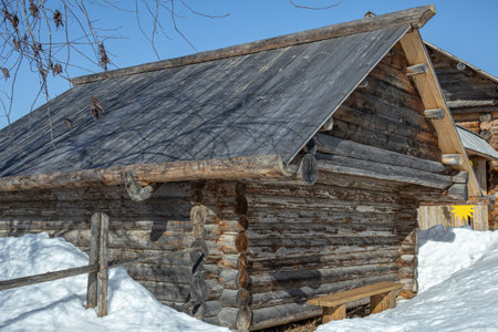 An old wooden barn built in the 19th century. Village barn in Khokhlovka. A barn for keeping livestock in the village in winter. A farm shed for animals.の写真素材