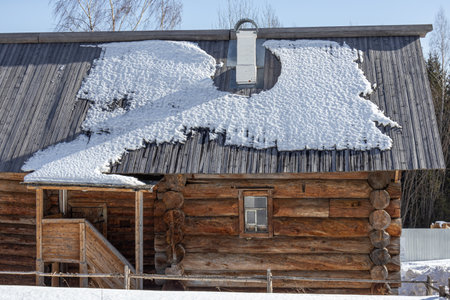 An old wooden log house built in the 19th century. Village house in Khokhlovka. Winter landscape in the village. There is snow on the wooden roof of the old house. Warming after winter frosts.の写真素材