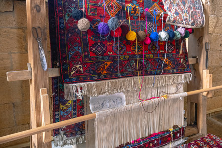 An antique loom for making all kinds of fleece, smooth fabrics and carpets. There is a club of multicolored yarn on a wooden loom. Handmade carpets made of natural yarn.の写真素材