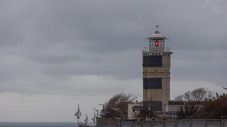A coastal lighthouse, which is used to mark the shores and determine the location of the vessel. A coastal landmark. A burning lighthouse lights the way to the shore for ships.の写真素材