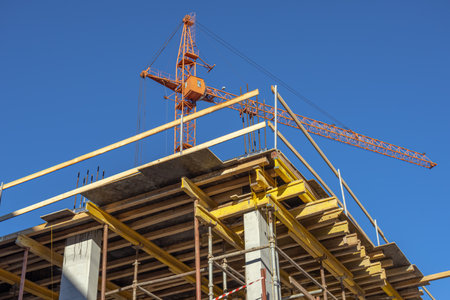 Equipment for the construction and lifting of bulky goods with construction materials. A tower crane at a construction site. Construction of load-bearing reinforced concrete columns at home.の写真素材