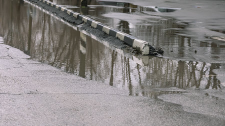 A puddle on a city street. A flooded road. Lack of drainage on the road. Incorrect drainage system design. Rainwater flooded the streets.の写真素材