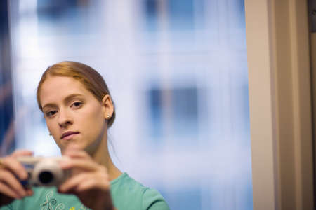 Serious young woman taking pictures with digital cameraの写真素材