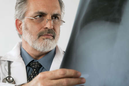 Cropped close-up portrait of a doctor wearing eyeglasses and a white lab coat and looking intently...