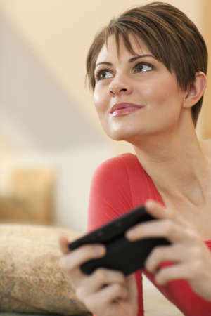 An attractive young woman is texting on a cellphone and smiling to the side. Vertical shot.