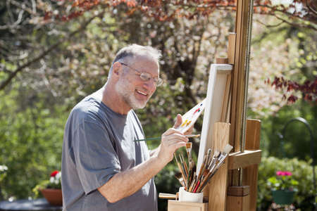 Man paints on an easel in a pleasant outdoor setting.の写真素材