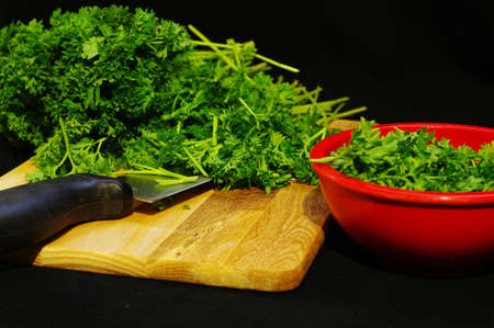 Chopped parsley with a knife and a red bowl