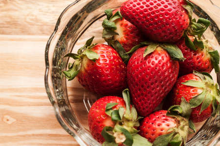 Strawberries in a glass bowl on a wooden board