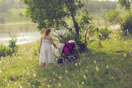 Woman with a baby stroller walks in the forestの写真素材