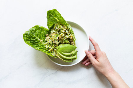 Avocado salad with quinoa and lettuce in a white plate on a white backgroundの写真素材