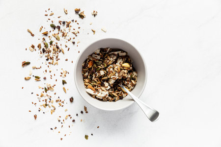 Healthy breakfast bowl with granola, nuts and seeds on white background