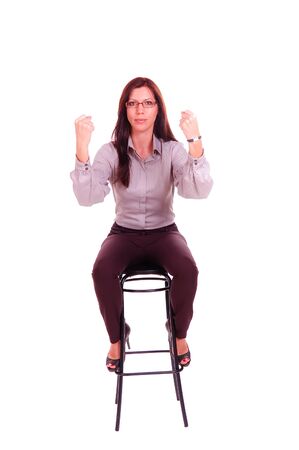 Young woman sitting on the stool with compressed fists isolated on the white backgroundの写真素材