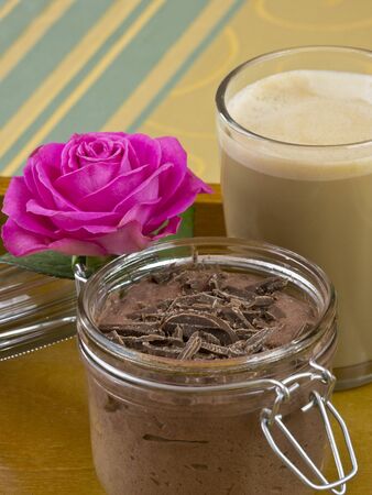 Chocolate pudding with a cup of coffee with milk and a pink roseの写真素材