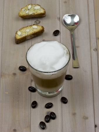 Latte macchiato with coffee beans and biscottiの写真素材
