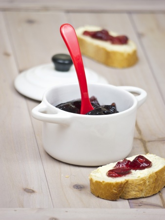 Red wine jelly in a ceramic pot with two slices of French breadの写真素材