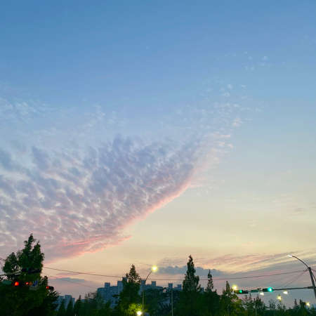 A view of a colorful cloud formation over the city at sunset.の写真素材