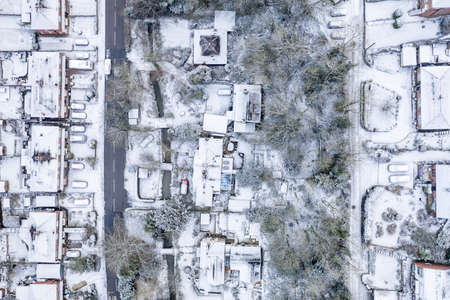 Top down aerial view over snow covered residential area. The thin layer of snow features textures and patters of architecture seeing from the bird's point of viewの写真素材