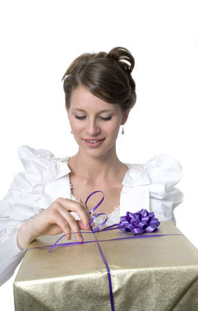 Young girl wears wedding dress and holds gift.  Photographed in studio.  の写真素材