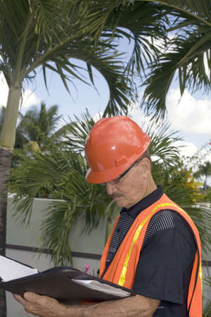 A senior looks at notes during the construction of a backyard in the tropics.  Photographed in...