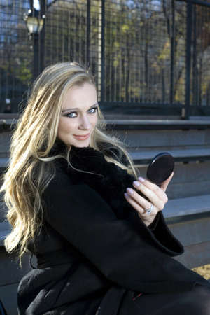 A Caucasian woman looks at camera while holding small mirror outdoors..の写真素材
