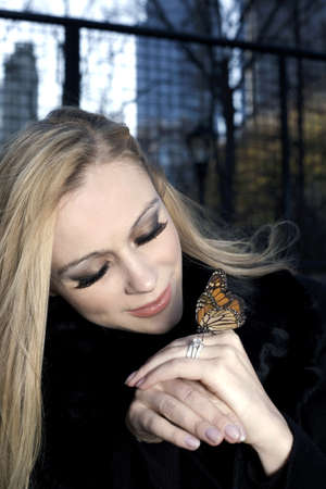 A Caucasian woman outdoors holding a butterfly insect.の写真素材