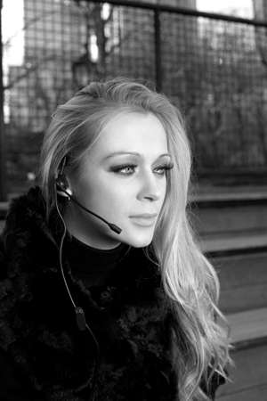 A blonde Caucasian woman outdoors using a headset phone.の写真素材