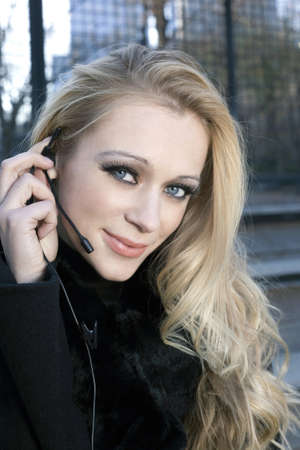 A blonde Caucasian woman outdoors using a headset phone.の写真素材
