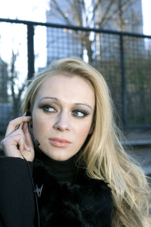 A blonde Caucasian woman outdoors using a headset phone.の写真素材