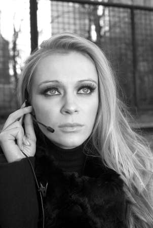 A blonde Caucasian woman outdoors using a headset phone.の写真素材