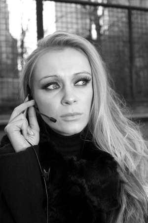A blonde Caucasian woman outdoors using a headset phone.の写真素材