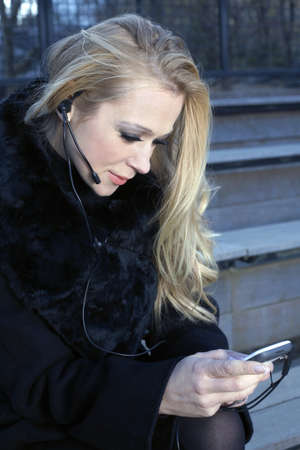 A blonde Caucasian woman outdoors using a headset phone.の写真素材