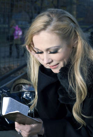 Caucasian woman holding a small Bible while outdoors の写真素材