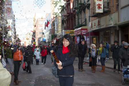 NEW YORK, NEW YORK - FEBRUARY 17: Young Asian woman tries out a Chinese firecracker during Chinese New Year Parade.  Taken FEBRUARY 17, 2013 in  NYC.のeditorial素材