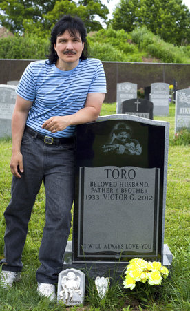 QUEENS, NEW YORK - JUNE 6:  nephew Eddie Toro visits grave of Yomo Toro, master of the Puerto Rican guitar like instrument called a cuatro on anniversary of his death.   Taken June 6, 2013 at Saint Michael's Cemetery in New York.のeditorial素材