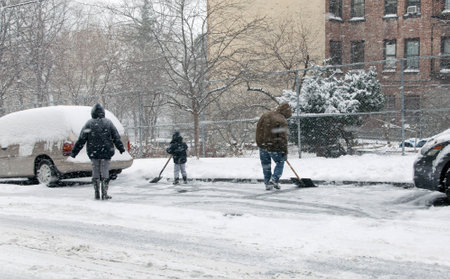 BRONX, NEW YORK - JANUARY 21  A family shovels snow during a 6 to 10 inch snow storm with teen temperatures along Ogden avenue and 162nd street   Taken January  21,  2014 in the Bronx,  New York のeditorial素材