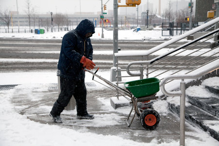 BRONX, NEW YORK, USA - FEBRUARY 19: Man uses salt spreader during snowfall.  Taken February 19, 2015 in the Bronx,  New York.のeditorial素材