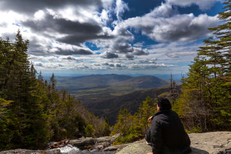 Man sitting and looking out from elevation on Mount Washinton via Ammonoosuc ravine trail in Coors County,  New Hampshire.の写真素材