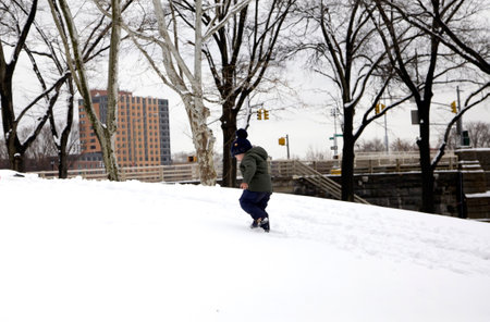 BRONX, NEW YORK/USA - March 2, 2019: Small child walks up snow hill in winter at Bronx park.のeditorial素材