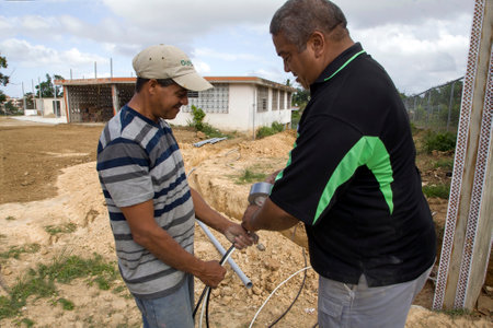 CERRO GOLDO, BAYAMON/PUERTO RICO - February 22, 2019: Two men work on wiring at a building construction site.のeditorial素材