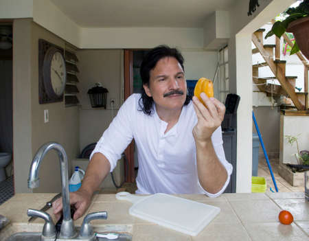 Hispanic mam looking at and holding star fruit at home.の写真素材