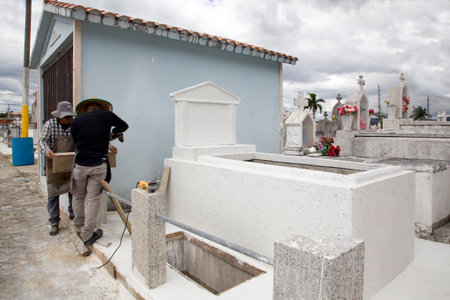 CERRO GORDO, SAN LORENZO/PR - February 7, 2019: Two men work on a crypt at municipal cemetery.のeditorial素材
