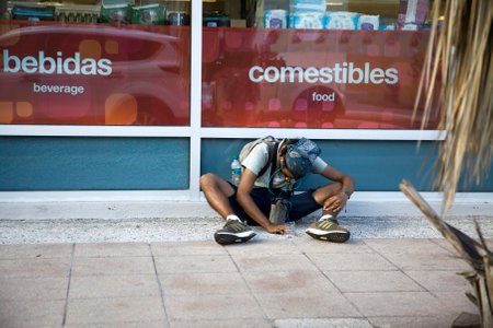 BAYAMON, PUERTO RICO/USA - February 10, 2019: Young man sits outdoors and begs for money.