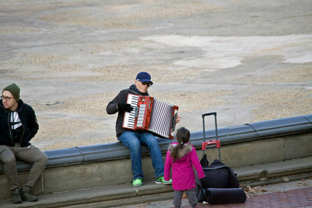 NEW YORK, NEW YORK/USA - November 11, 2018: Senior man playing accordian as little girl watches in Central Park.のeditorial素材