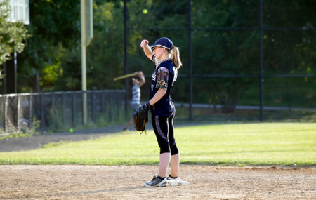 BRONX, NEW YORK/USA - August 10, 2019: Female pitcher uses hand to cover glare during game in public park near Yankee Stadium.のeditorial素材