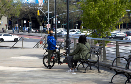 BRONX, NEW YORK/USA - April 25, 2020: Kid on bike with mask and adult nearby during COVID-19 pandemic.のeditorial素材