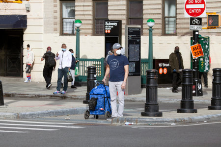 BRONX, NEW YORK/USA - May 18, 2020: Man wearing mask prepares to cross street with his laundry.のeditorial素材