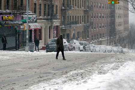BRONX, NEW YORK, USA - January 29, 2022: Man crossing street during snow fall.のeditorial素材