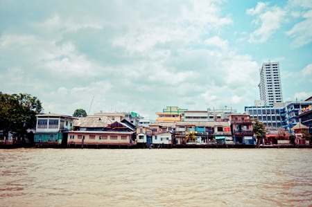 BANGKOK, THAILAND - AUGUST 03: residential buildings seen from boat along the Chao Phraya River in Bangkok on 03 august 2012. The Chao Phraya is a major river in Thailand, it flows through Bangkok and then into the Gulf of Thailand.のeditorial素材