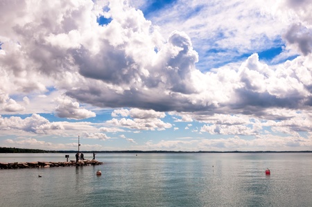 fishers on pier and cloudy dramatic sky over Garda lake - Italyのeditorial素材