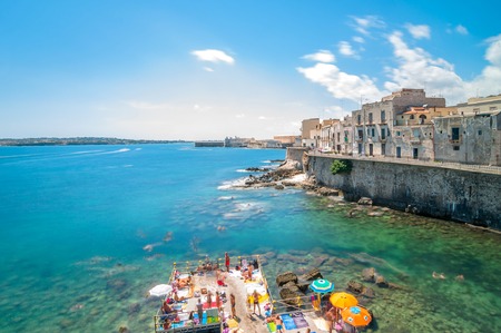 SYRACUSE, ITALY - AUGUST 17, 2014: tourists and locals enjoy blue mediterranean sea in Ortigia, Syracuse, Italy. Ortigia is a small island which is the historical centre of the city of Syracuse, Sicily.のeditorial素材